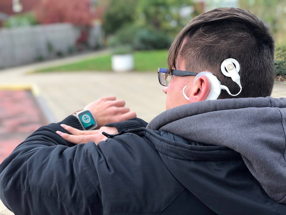 User with hearing aid showing the 'you have arrived' icon on their watch