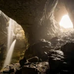 Apache Death Cave photos showing dark cave interior with waterfall and light streaming through Canyon Diablo